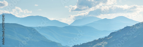 Mountain ranges in blue haze, evening light, panoramic view. 