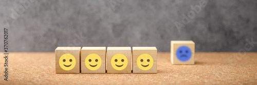 cubes with happy emoticons as a group and unhappy ones in the back on concrete background photo
