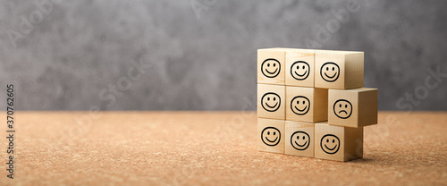cubes with happy emoticons as a group and one unhappy one on concrete background photo
