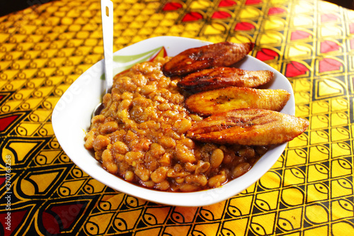 Foto A meal of porridge beans and fried plantain with a spoon at the side
