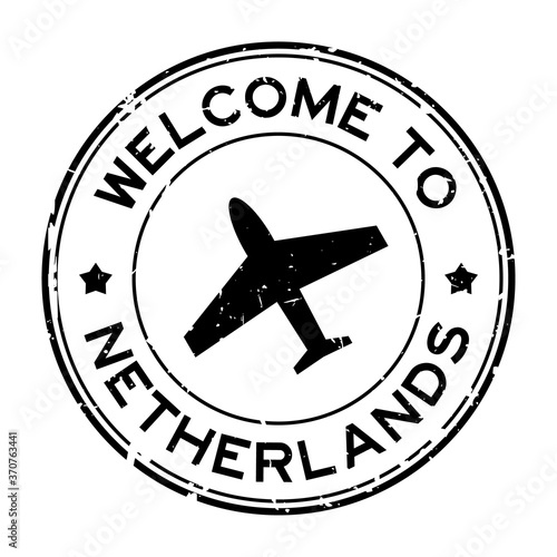 Grunge black welcome to Netherland word with airplane icon round rubber seal stamp on white background photo