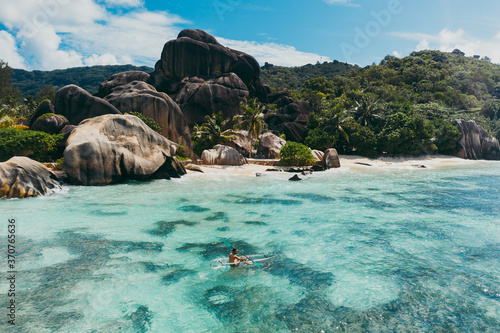 "La digue" island in Seychelles. Silver beach with granitic stone, and jungle. Man enjoying vacations on the beach and having fun with kayak. Aerial view shot with drone