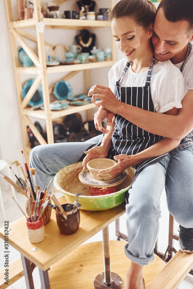 With her boyfriend or husband. Young female ceramist have a works indoors with handmade clay product. Conception of pottery With her boyfriend or husband. Young female ceramist have a works indoors with handmade clay product. Conception of pottery