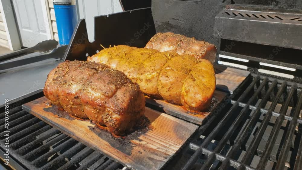 Home cooking - Three half loin pork being slowly smoked and baked on cedar planks on gas grill. Home cooking - Three half loin pork being slowly smoked and baked on cedar planks on gas grill.