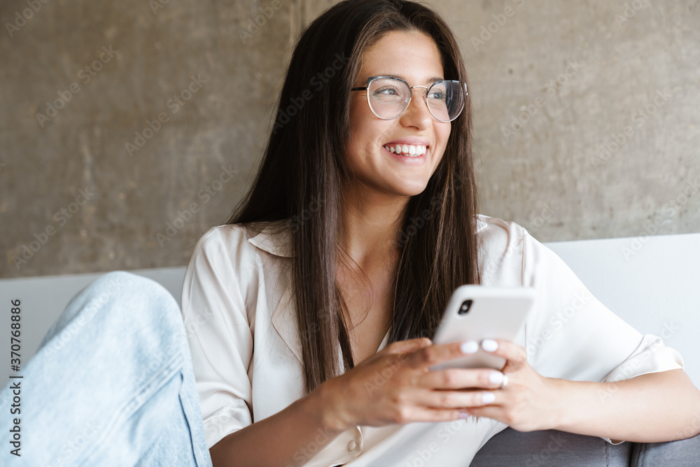 Happy young woman sitting on sofa and reading sms Happy young woman sitting on sofa and reading sms
