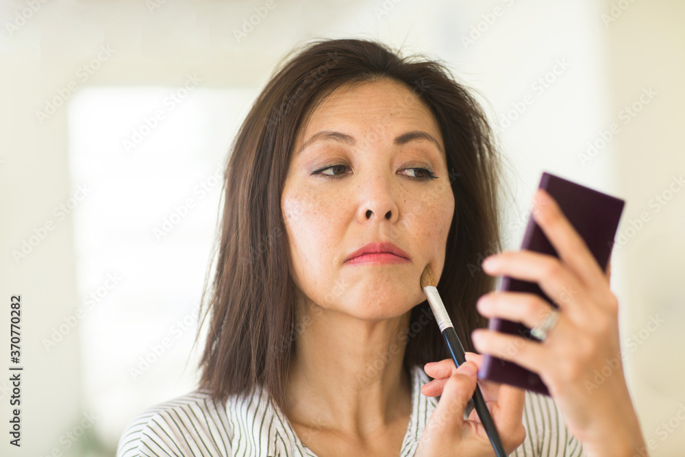 Portrait of a Asian woman applying make up. Portrait of a Asian woman applying make up.