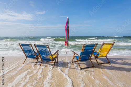 Four empty beach chairs being overtaken by incoming tide