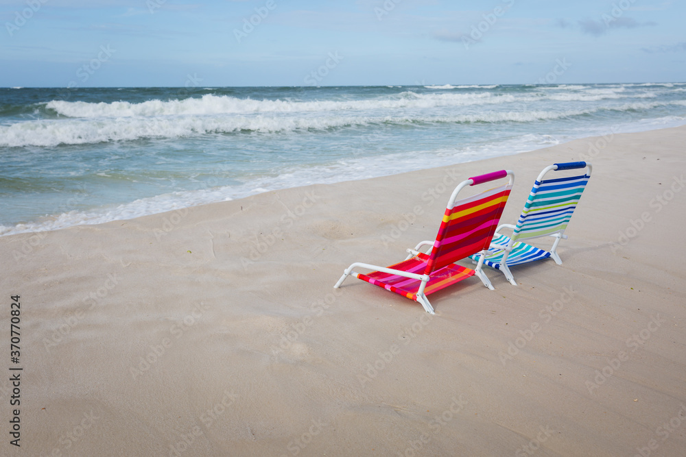 Two empty beach chairs facing the ocean Two empty beach chairs facing the ocean