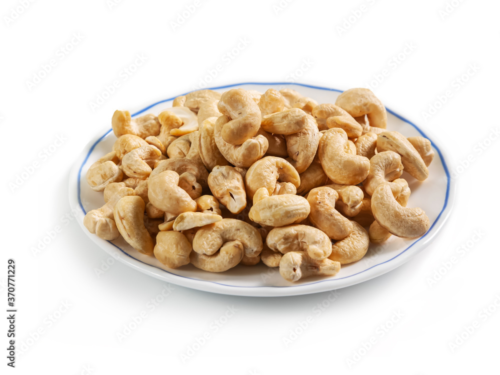 cashew peeled nuts on a white saucer with a blue border, isolated on a white background cashew peeled nuts on a white saucer with a blue border, isolated on a white background