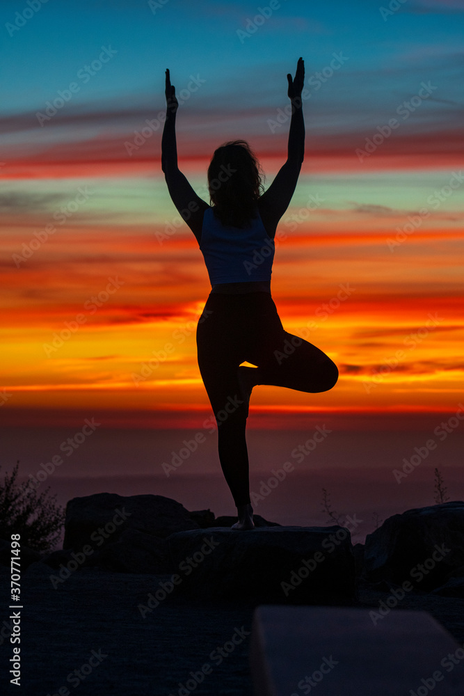 Silhouette of a young woman doing yoga in the sunset