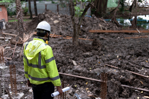 Civil Engineer People wearing safety helmet while inspection detail on construction site with drawing blueprint. Surveyor and checking building foundation structure on soil.