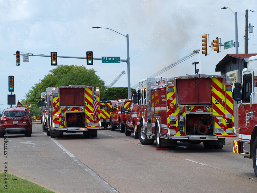 Fire trucks line up at a 4-alarm fire in a large shopping center. 
