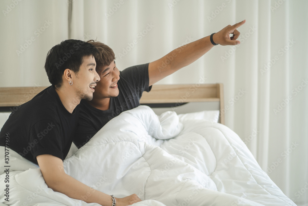 Happy gay couple lying on bed at home