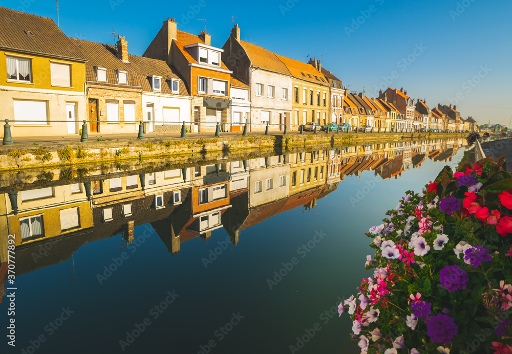 Line of Traditional buildings with cars standing and canal in foreground in a city of Saint-Omer, Summer in France.