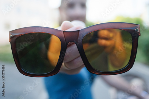 Sunglasses in female hands close up.