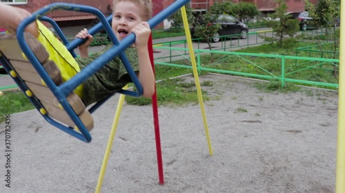 A preschool boy swinging on a swing in a playground, video