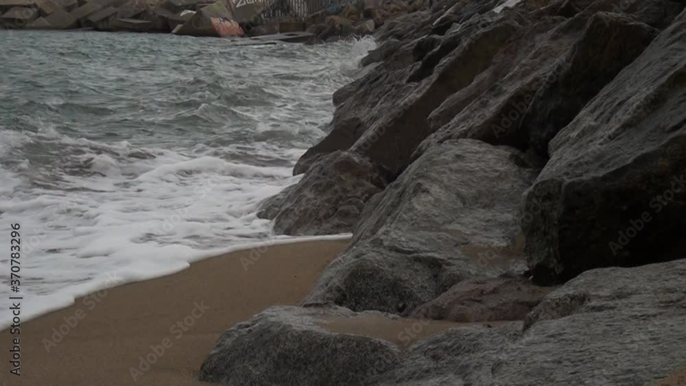 Olas rompiendo contra rocas en la costa, con playa. Olas rompiendo contra rocas en la costa, con playa.