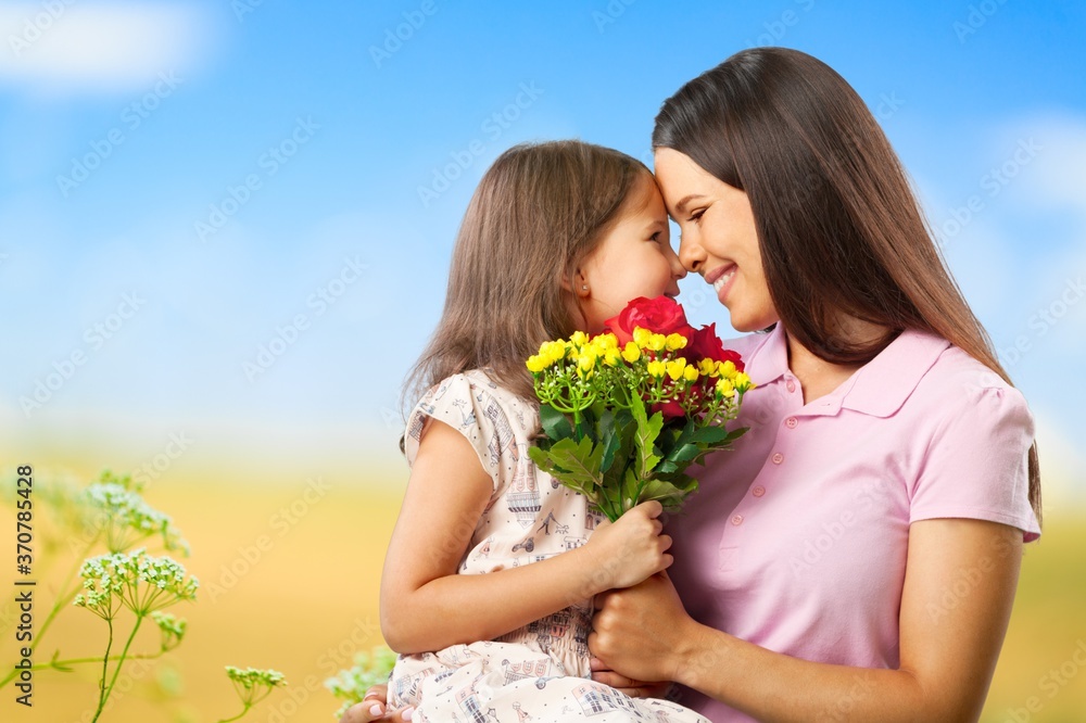 Mother and daughter with bouquet of flowers on blurred background. Mother and daughter with bouquet of flowers on blurred background.