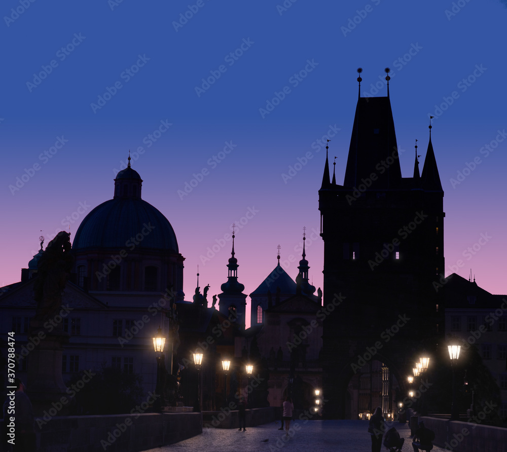 Charles Bridge at dawn. Panoramic image, silhouette of Bridge Tower and churches, street lights in Prague, Czech Republic.