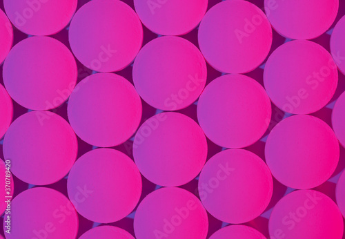 Geometrc pattern of round medical pills on pink background