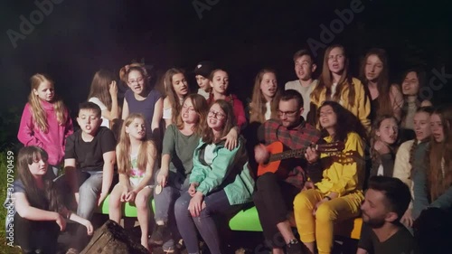 Kids singing near camp fire.