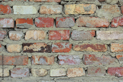 Part of a brick wall with bricks of different colors.