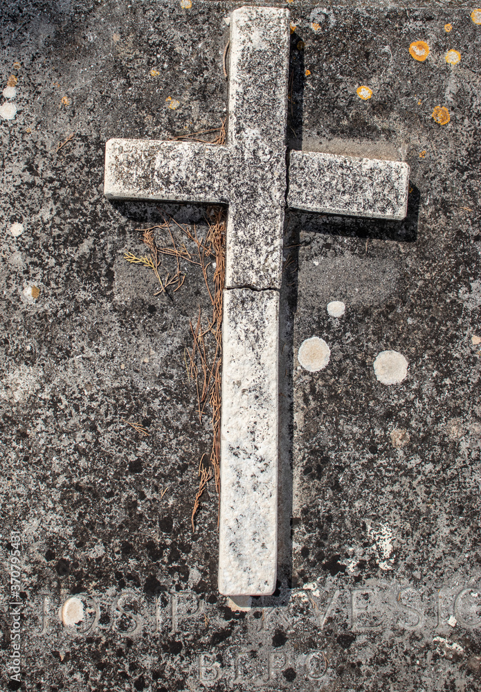 Old simple cross standing on a grave, bent and ruined over time. Hunders of years old on a christan graveyard