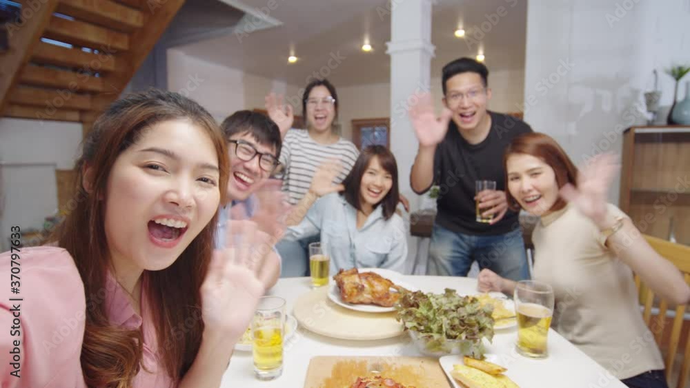 Group of young Asian people at home dinner party, looking at camera, greeting friends on remote video call. Point of view vlog or selfie camera. New normal lifestyle, social distancing concept Group of young Asian people at home dinner party, looking at camera, greeting friends on remote video call. Point of view vlog or selfie camera. New normal lifestyle, social distancing concept
