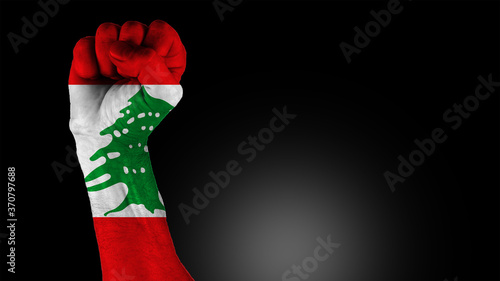 Obraz na płótnie Concept of an uprising and political turmoil in Lebanon. Low key picture of a fist painted in colors of the Lebanese flag on a black background. w salonie