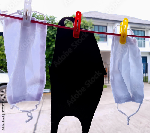 Cloth masks drying on clothesline in front of the house. Washing and drying cloth mask is for cleanliness and reuse. Covid-19 prevention concept.