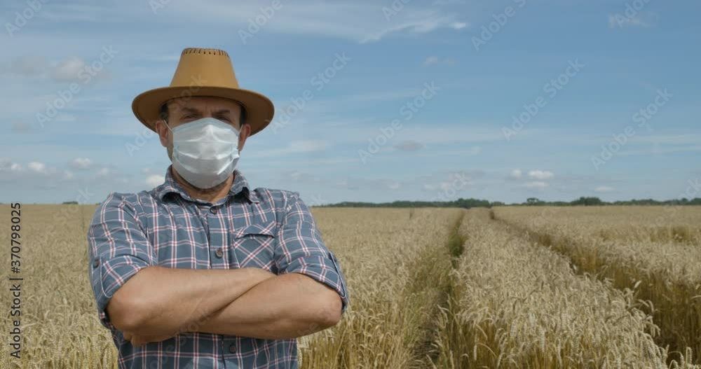 Corona Virus Face Mask Covid-19. Portrait Caucasian Farmer Man in Plaid Shirt in Hat Looking at Camera. Farmer Man in Face Mask for Covid-19 Standing in Wheat Field. Farm Worker. Epidemic Coronavirus. Corona Virus Face Mask Covid-19. Portrait Caucasian Farmer Man in Plaid Shirt in Hat Looking at Camera. Farmer Man in Face Mask for Covid-19 Standing in Wheat Field. Farm Worker. Epidemic Coronavirus.