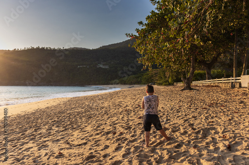 Menino de costas, parado, observando a praia e o por do sol. Litoral brasileiro.