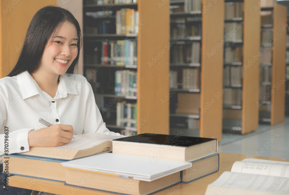 Young Asian female college students research and learn from textbooks in the university library Young Asian female college students research and learn from textbooks in the university library