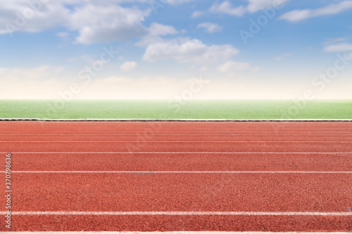 Running track with copy space. Empty athlete track with grasses, blur cloud and blue sky.