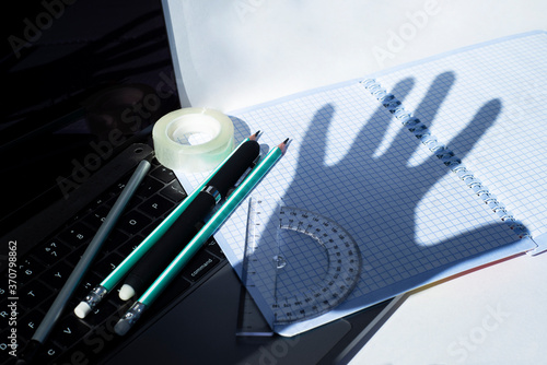 Distance education and distance work. Notebook Stationery and medical masks. Fancy shadows on a checkered notebook. The idea of ​​non-acceptance Protest.