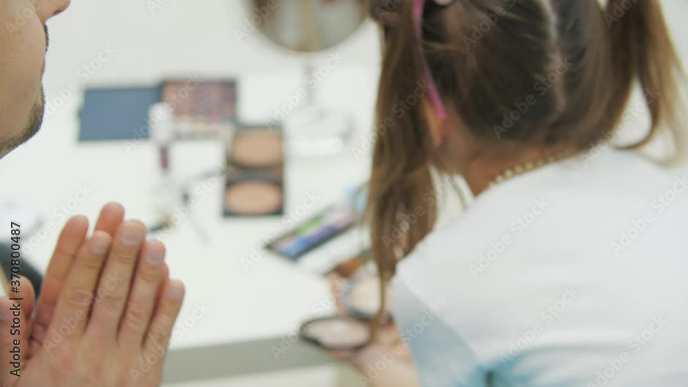 Closeup of little kid doing make-up for her daddy. Dad is looking with silly face expression. Closeup of little kid doing make-up for her daddy. Dad is looking with silly face expression.