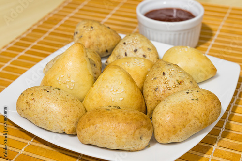 Salgados assados tipicamente brasileiros servidos dentro de um prato branco. Esfiha, bolinhos, empadas, de carne e frango. Salgados para festa. 