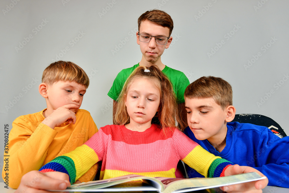 Three brothers and a sister thoughtfully read a book. Three brothers and a sister thoughtfully read a book.