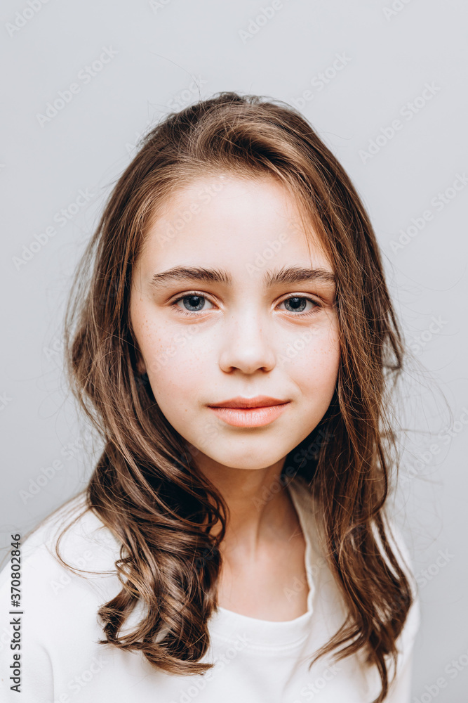 little pretty girl with expressive facial features posing for a photo on a gray background little pretty girl with expressive facial features posing for a photo on a gray background