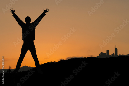 Silhouette eines Mannes mit den Armen hoch vor imposanter Landschaft