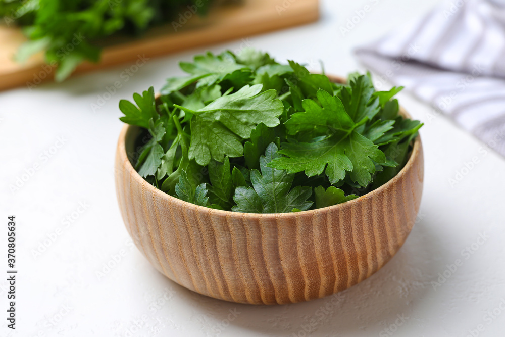 Fresh green parsley in wooden bowl on white table Fresh green parsley in wooden bowl on white table