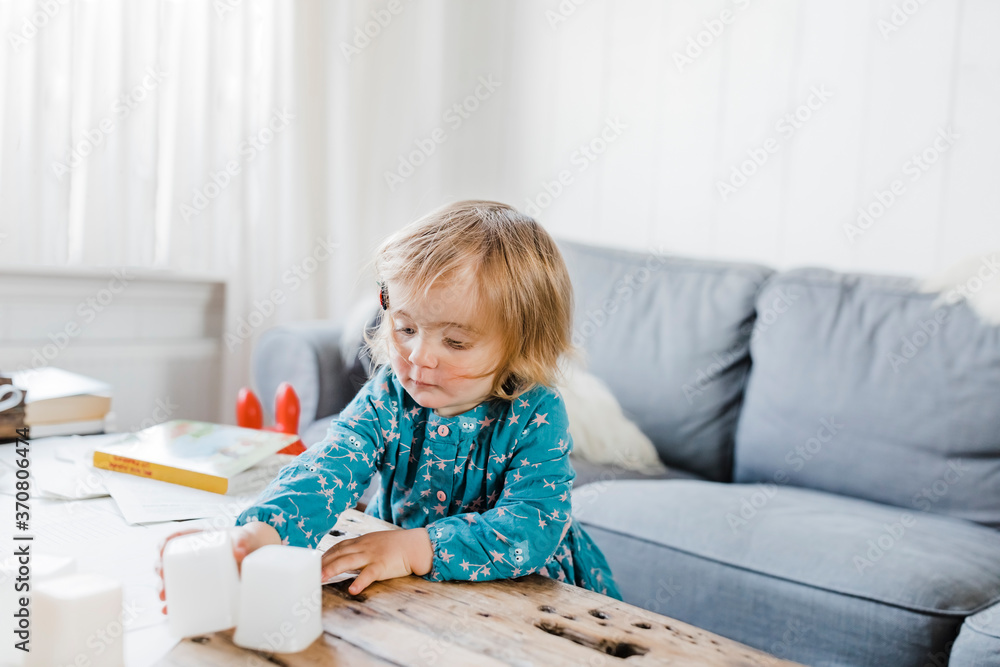 Toddler girl playing with plastic containers on table Toddler girl playing with plastic containers on table
