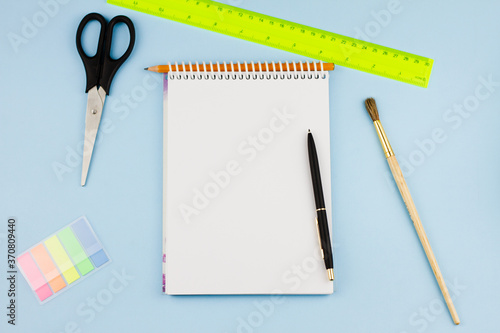 Assorted colorful office supplies on a light blue background. View from above. Education concept.