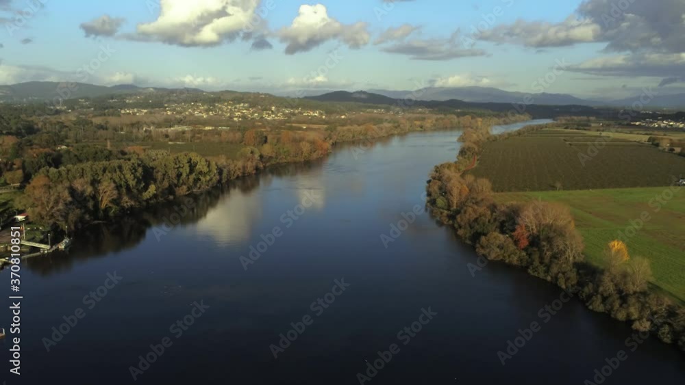 Beautiful aerial view of big white clouds and green trees reflecting on the calm waters of the Miño river, located in Pontevedra province, city of Tui - Spain. Beautiful aerial view of big white clouds and green trees reflecting on the calm waters of the Miño river, located in Pontevedra province, city of Tui - Spain.