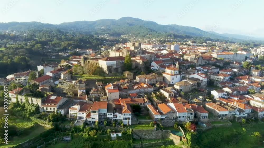 Aerial view of a beautiful little village in the city of Tui, located in Pontevedra province, Spain. Gable roof houses surrounded by trees and green hills. Aerial view of a beautiful little village in the city of Tui, located in Pontevedra province, Spain. Gable roof houses surrounded by trees and green hills.