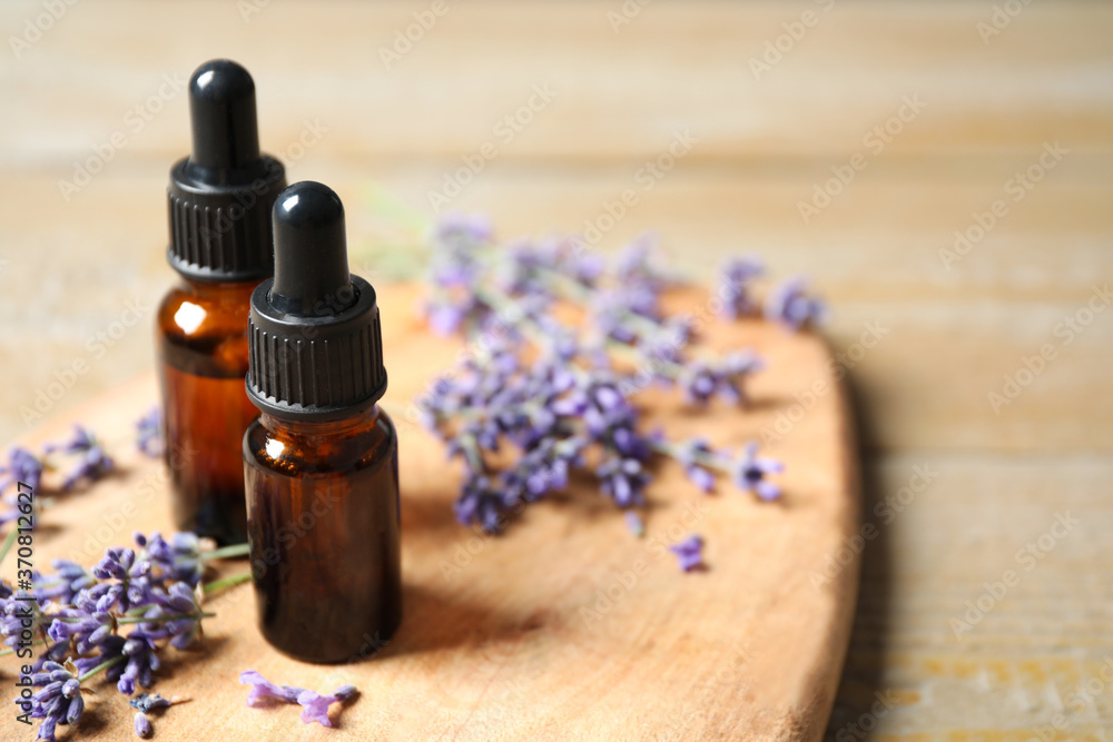 Bottles of essential oil and lavender flowers on wooden table. Space for text Bottles of essential oil and lavender flowers on wooden table. Space for text