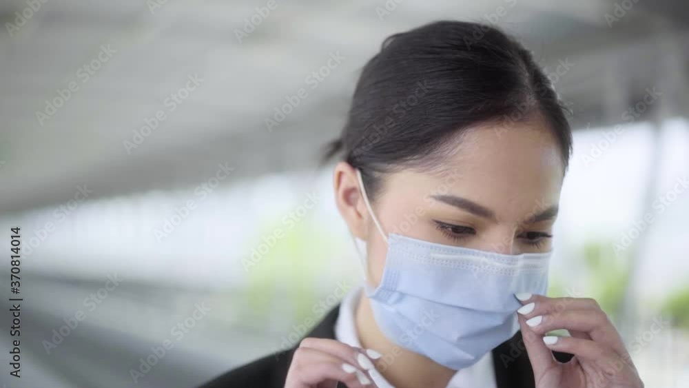 Young asian woman business live in airport, She wearing face mask for protect virus air pollution on safety travel and look back to audience with beautyfull eyes on footbridge. Slow Motion Shot. Young asian woman business live in airport, She wearing face mask for protect virus air pollution on safety travel and look back to audience with beautyfull eyes on footbridge. Slow Motion Shot.