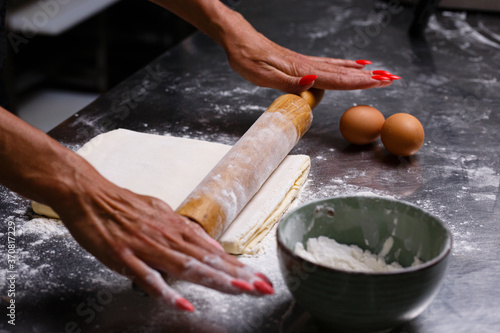 The chef prepares pastries in a professional kitchen. Dark background.