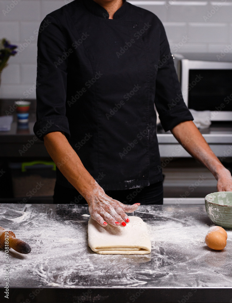The chef prepares pastries in a professional kitchen. Dark background. The chef prepares pastries in a professional kitchen. Dark background.