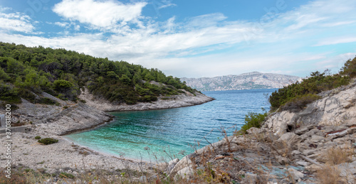 Fototapeta Naklejka Na Ścianę i Meble -  Hidden cove beach on the island of Brac, Croatia. Rocky shore with forest trees surrounding the small paradise. Area in front of the hidden bunker belonging to Yugoslavian leader Tito